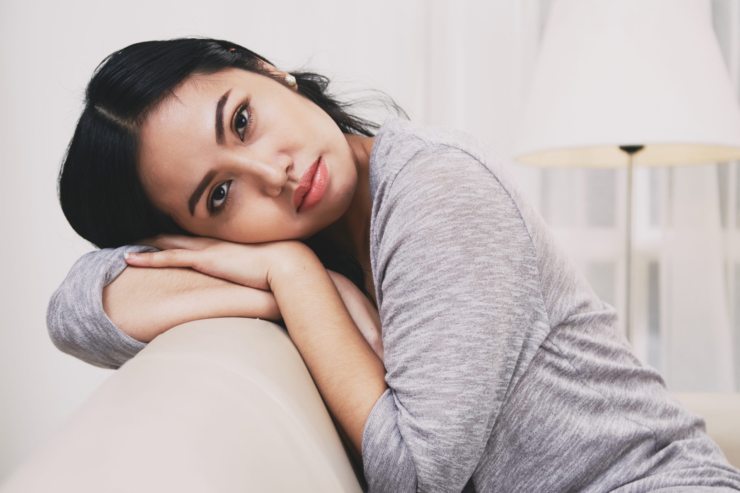 Wanita berehat dengan ekspresi letih dan wajah kurang bermaya di dalam rumah