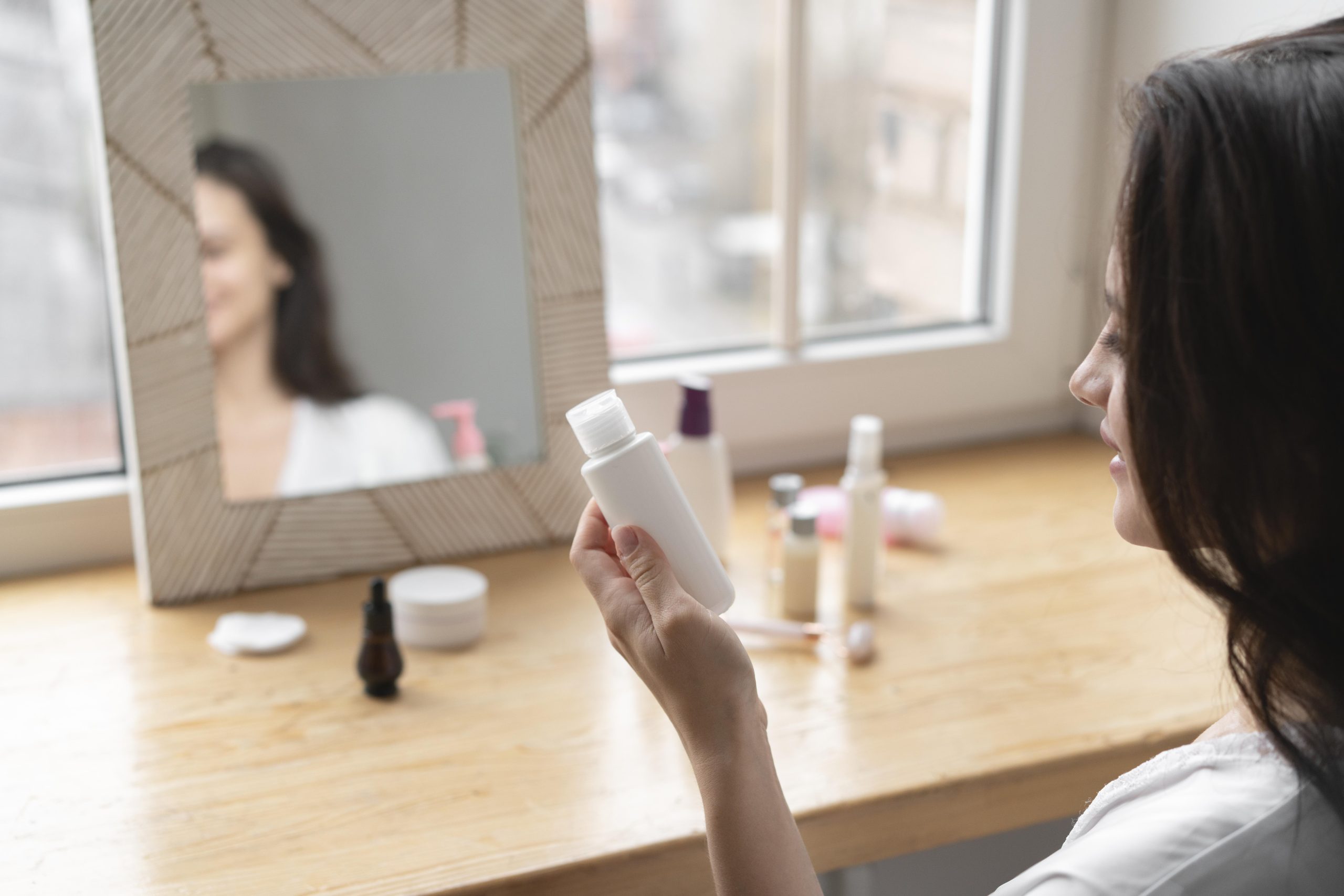 wanita asia melakukan basic skincare routine di depan cermin